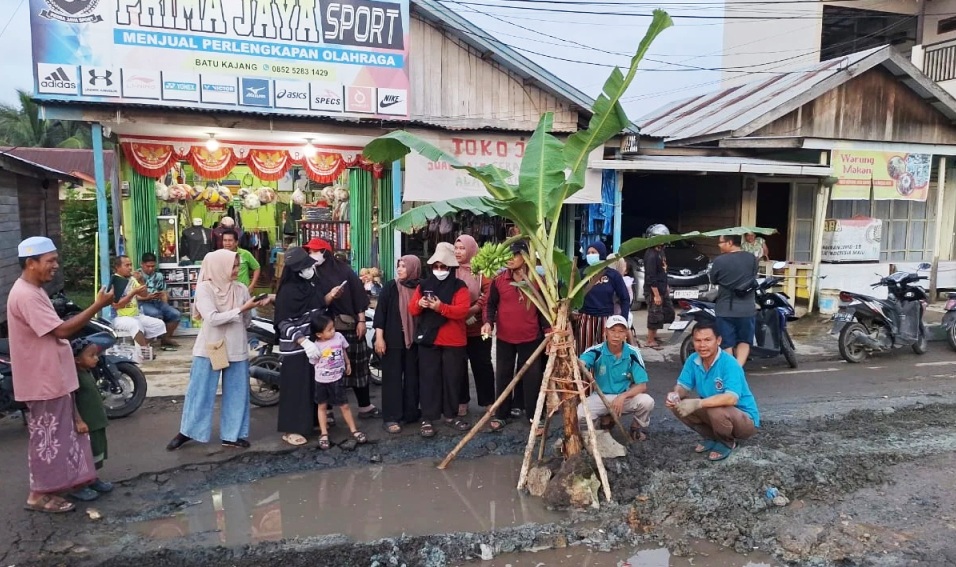  Aspiana bersama warga menanam pohon pisang di lubang jalan kawasan Batu Kajang. Foto: Ist